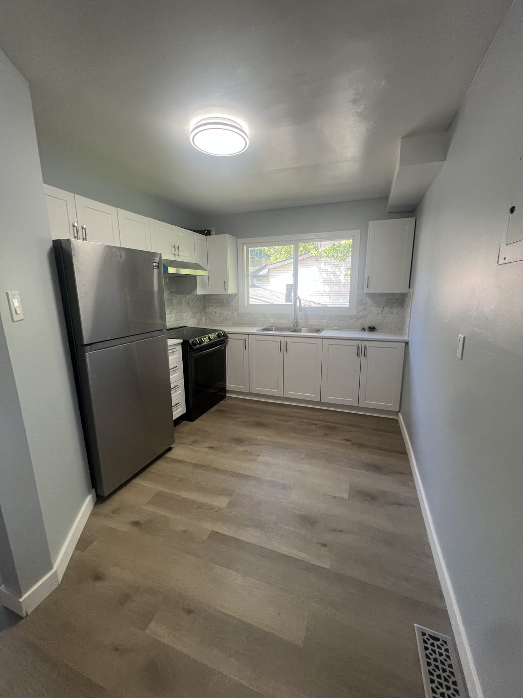 Renovated kitchen with white cabinets and plank flooring